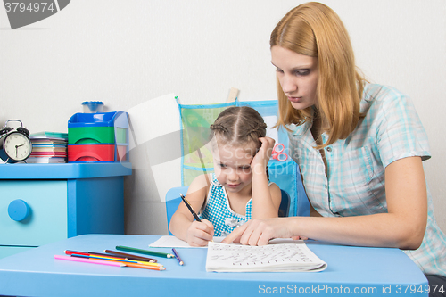 Image of  Tutor teaches the child to write letters