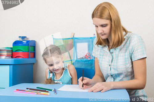 Image of Educator shows the five-year child draw with pencils