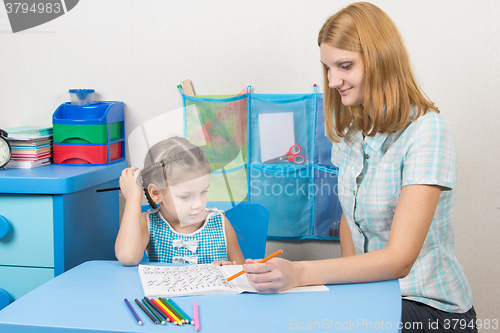 Image of Five-year girl draws pencil in a notebook and looked into the frame