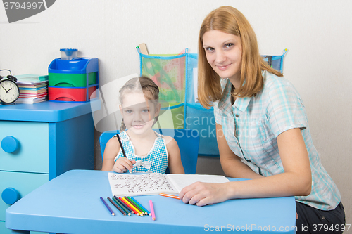 Image of Young girl sitting at a table with a five-year girl and deals with spelling