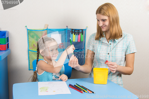 Image of Five-year girl takes pencil from mother hands