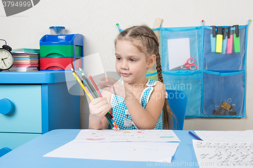 Image of Happy five year old girl picked up a colored pencils and choose the right pencil