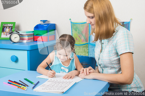 Image of Five-year girl learns to write letters correctly, a tutor helps her