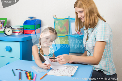 Image of Tutor checks the job done on a piece of a five-year girl