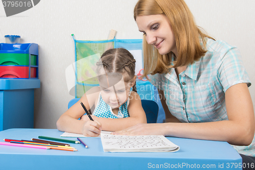 Image of Tutor sees that the child turns out to write letters of the alphabet