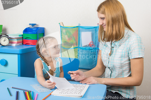 Image of Five-year girl tutor shows the completed task on a sheet