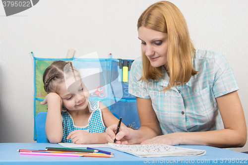 Image of A young girl explains the five-year girl how to write letters