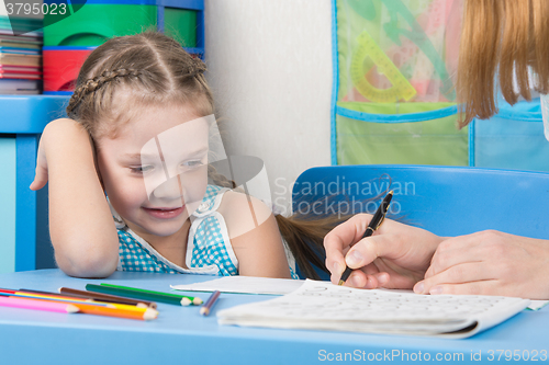 Image of Five-year girl with a smile looking at my mother explaining how to write letters