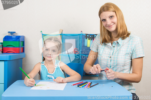 Image of The five-year child draws on a sheet of paper, pencils undermines mom