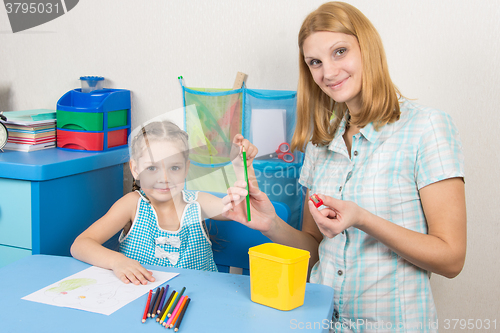 Image of The five-year child put a finger on the tip of a pencil mother, and together looked in the frame