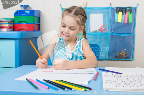Image of Five-year girl stuck out her tongue with pleasure, drawing picture at table