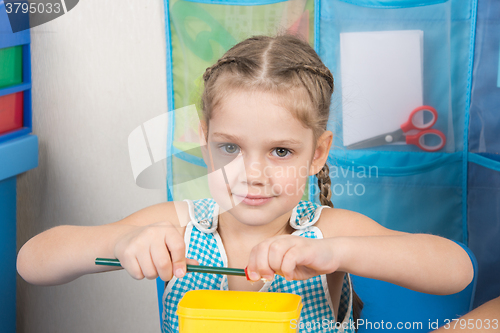 Image of Happy five year old girl sharpens a pencil sharpener small