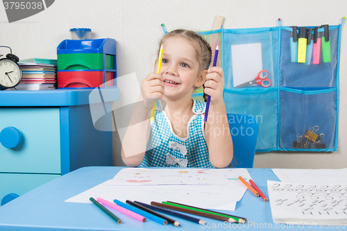 Image of Happy five year old girl chooses the correct pencil drawing at the table