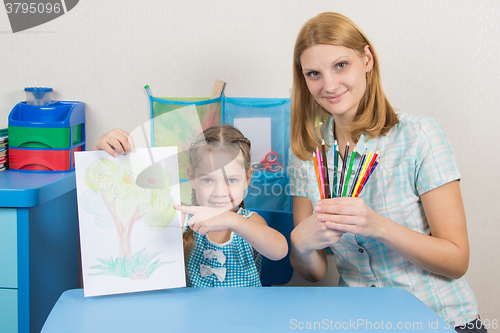 Image of Five-year girl showing on the picture, my mother keeps in the hands of colored pencils