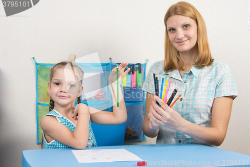 Image of The five-year child chose the correct pencil from mother hands and looked into the frame