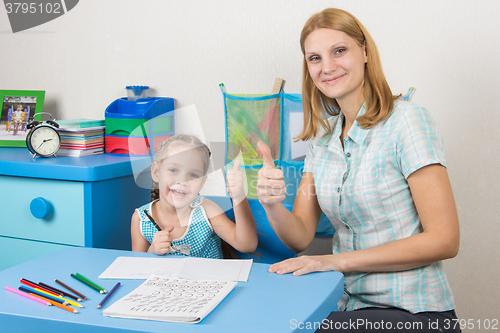 Image of Mentor and five-year girl joyfully show the thumbs up by doing a regular job