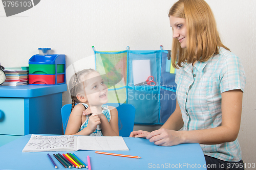Image of The girl is happy and looks at the teacher in kindergarten