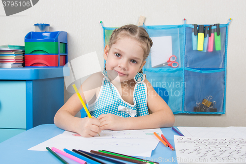 Image of Happy five year old girl draws pencil and looked into the frame