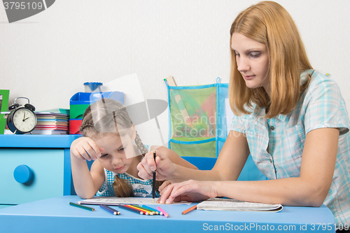 Image of A girl interested look like mom paints a stencil