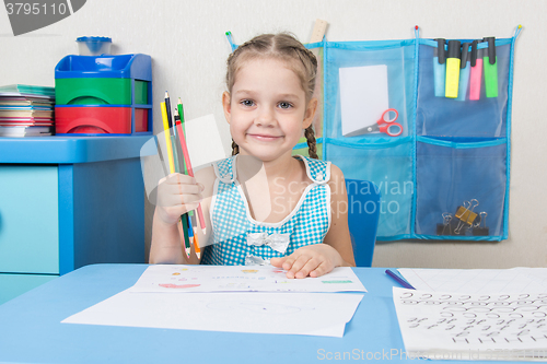 Image of Happy five year old girl picked up a colored pencil and looked into the frame