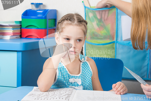 Image of Five-year girl thought doing spelling under the supervision of a tutor