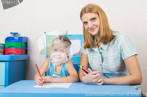 Image of Mentor and five year old child draw with pencils sitting at the table