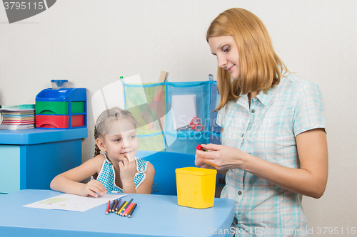 Image of Five-year girl with interest looks like mom sharpens pencils