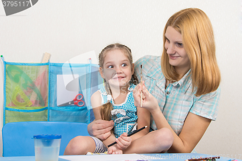 Image of Mentor and five year old girl having fun looking at the brush to draw