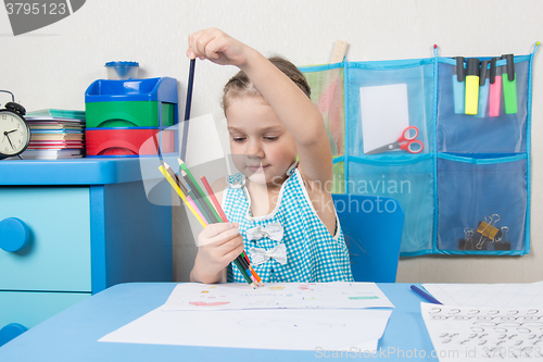 Image of Happy five year old girl chose the correct pencil from the heap