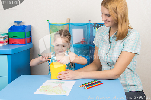 Image of My mother helps the child to sharpen pencils