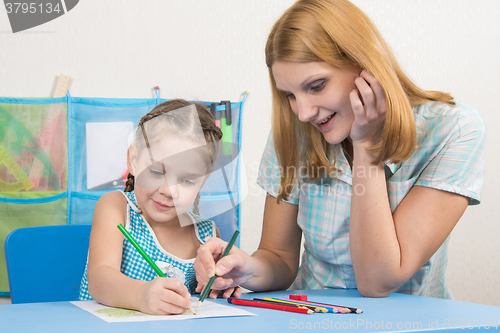 Image of Five-year girl and young mother together paint a picture with crayons