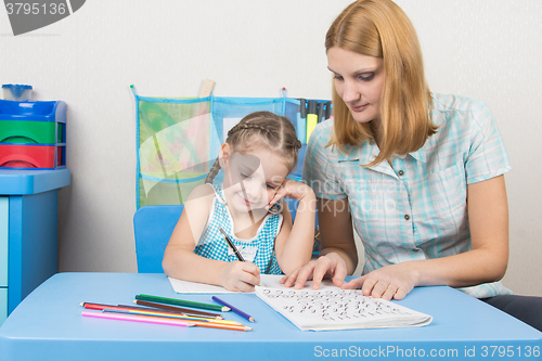 Image of Young mother prepares a five-year girl to school