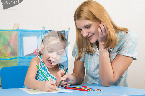 Image of Five-year girl and young mother having fun drawing happy drawing with crayons