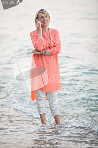 Image of Woman talking on mobile phone at the seaside