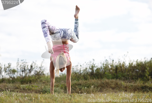 Image of Agile young woman doing a handstand