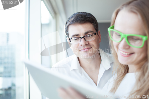 Image of Happy businesspeople working with tablet PC in the office