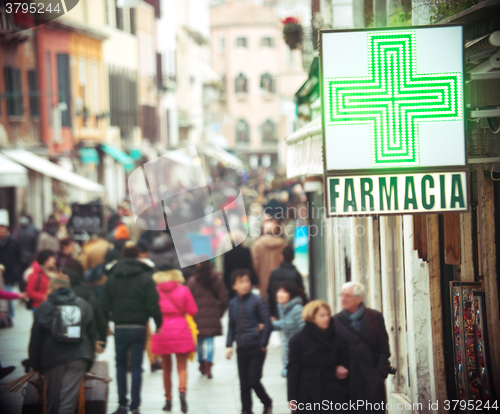 Image of Pharmacy sign hanging on the building in crowded street