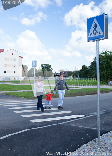 Image of Family of three crossing the road.