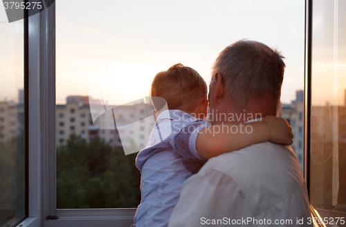 Image of Grandfather and grandson embracing on the balcony