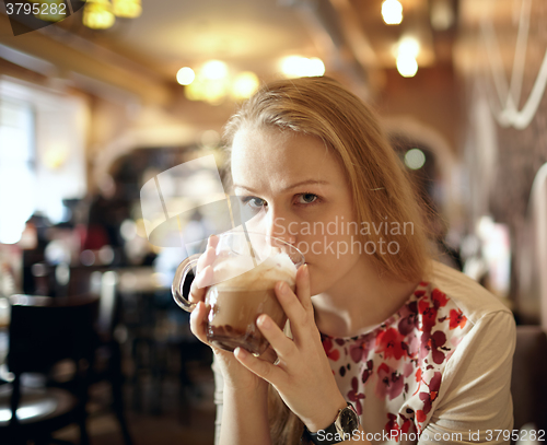 Image of Girl is drinking latte in cafe.