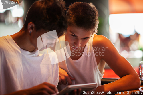 Image of Young men using tablet computer in cafe