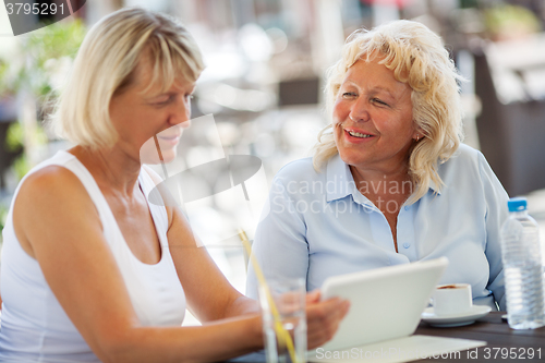 Image of Senior women spending time with pad in outdoor cafe