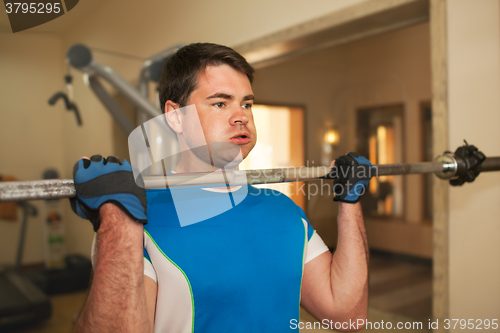 Image of Strong young man exercising with barbell