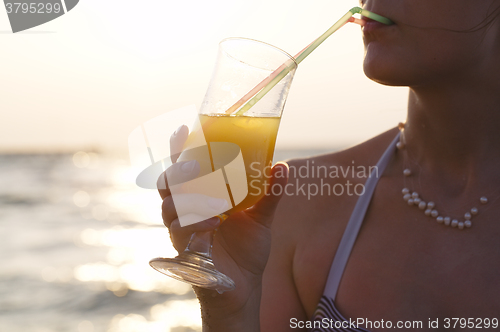 Image of Woman sipping a refreshing cocktail at sunset