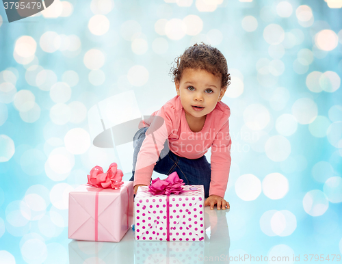 Image of baby girl with birthday presents and confetti