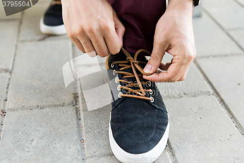 Image of close up of male hands tying shoe laces on street