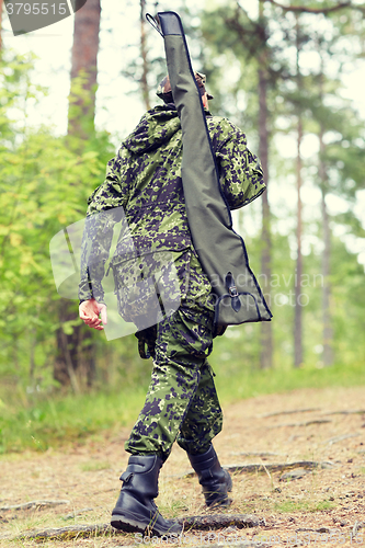 Image of young soldier or hunter with gun in forest