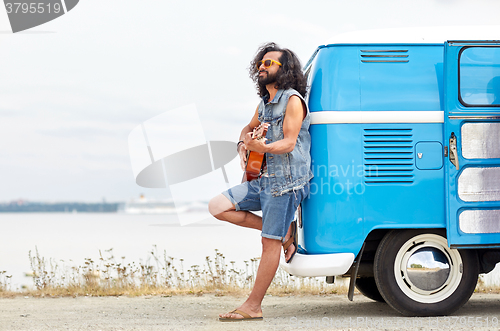 Image of hippie man playing guitar over minivan on beach
