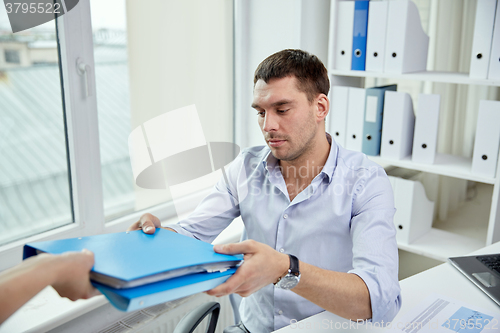 Image of businessman taking folder from secretary in office