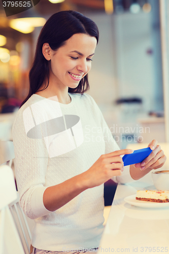 Image of smiling woman with smartphone and coffee at cafe